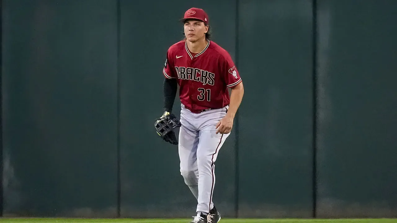 McCarthy wears a red D-backs jersey and waits in the outfield.