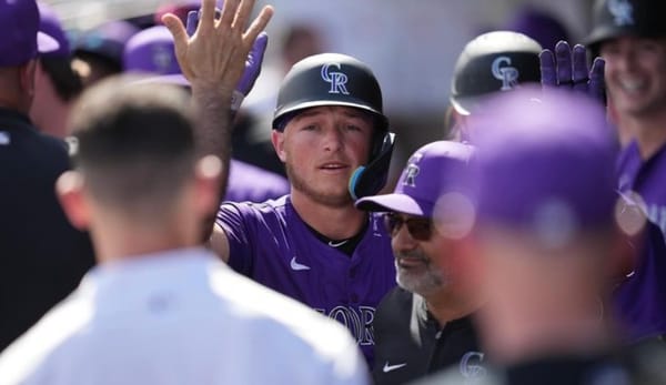 Hunter Goodman high-fives his teammates after hitting a home run in spring training. He’s wearing purple and looking, justif